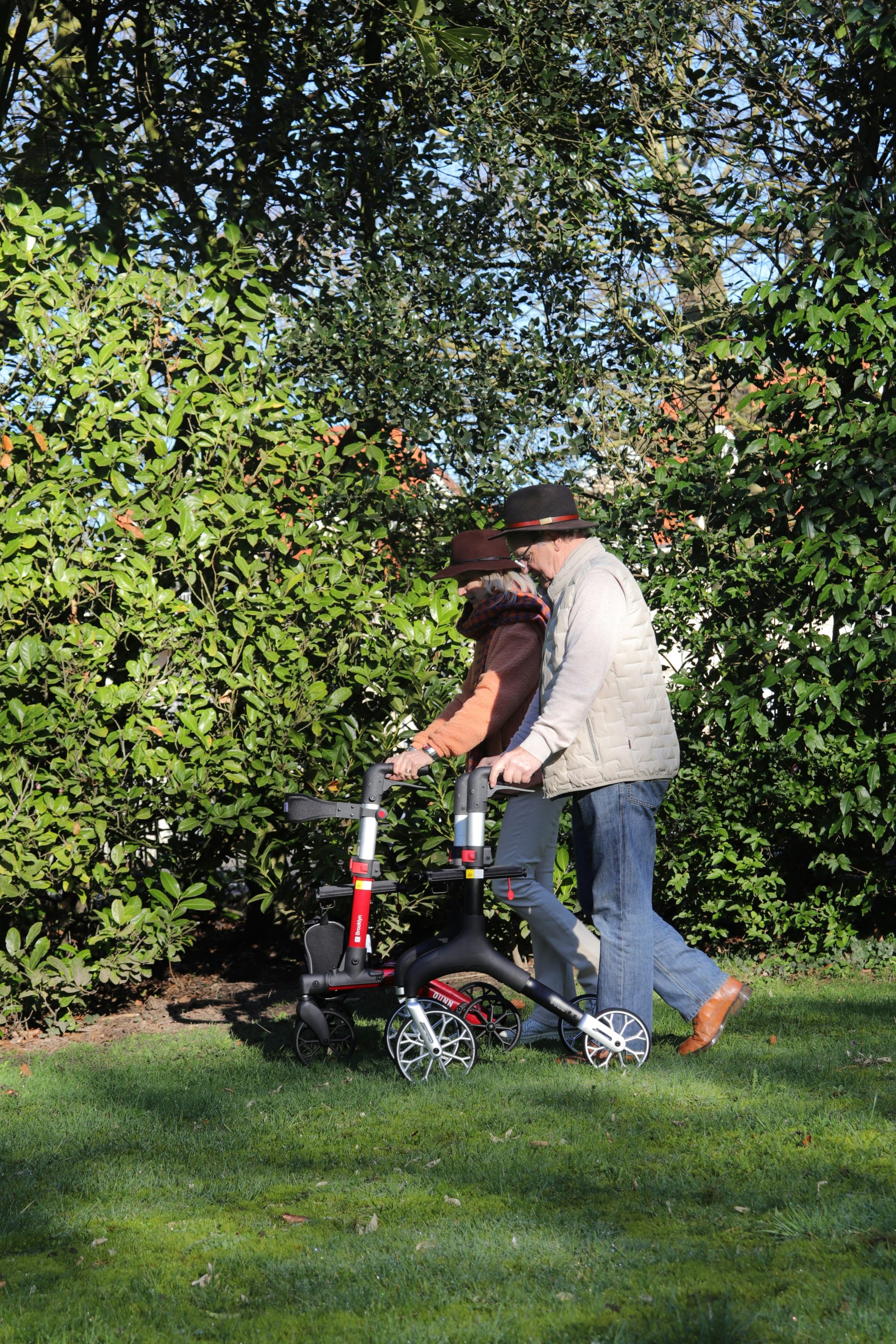 Pareja de ancianos paseando con un andador en un jardín.